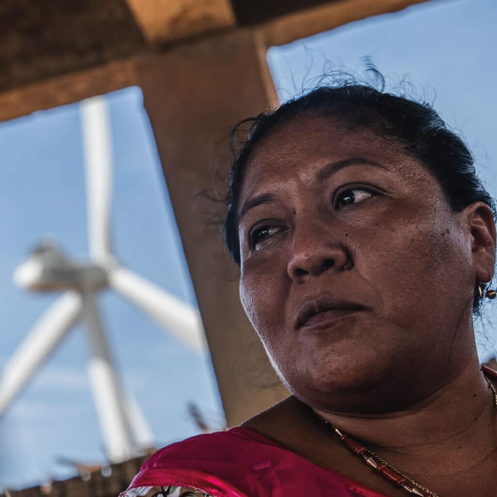 Mujer Wayuú con un parque eólico atrás en la Guajira.